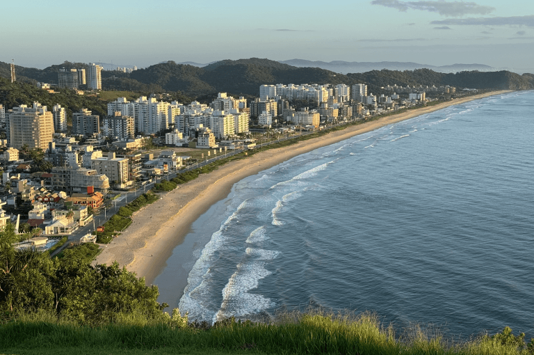 Vista aérea panorâmica do Morro do Careca em Itajaí, evidenciando a orla, as praias e a vegetação exuberante do litoral catarinense.