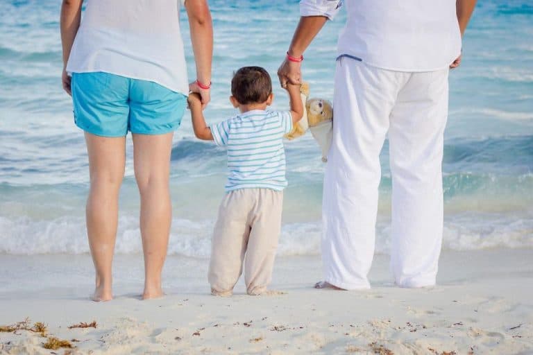 Família com criança pequena de mãos dadas observando o mar em uma praia tranquila de Itajaí, simbolizando lazer familiar no litoral catarinense.